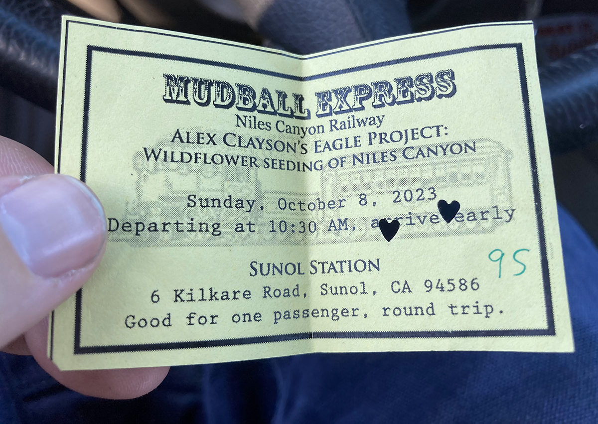 A ticket for the Mudball Express being held in a person's hand.